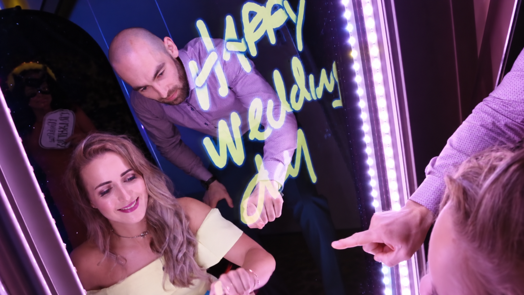 A couple drawing a personal message on the mirror booth touchscreen