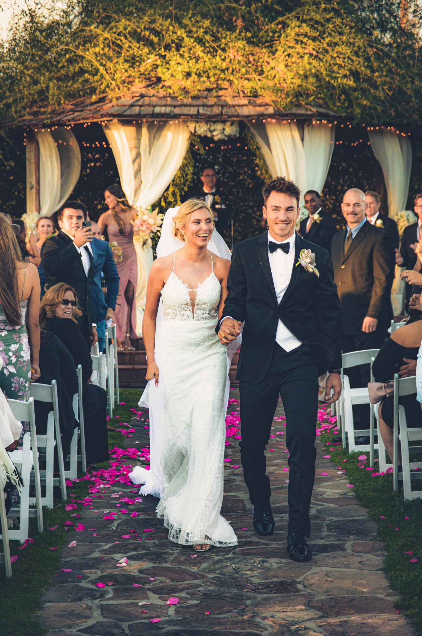 A smiling bride and groom walking down the aisle after their outdoor wedding ceremony