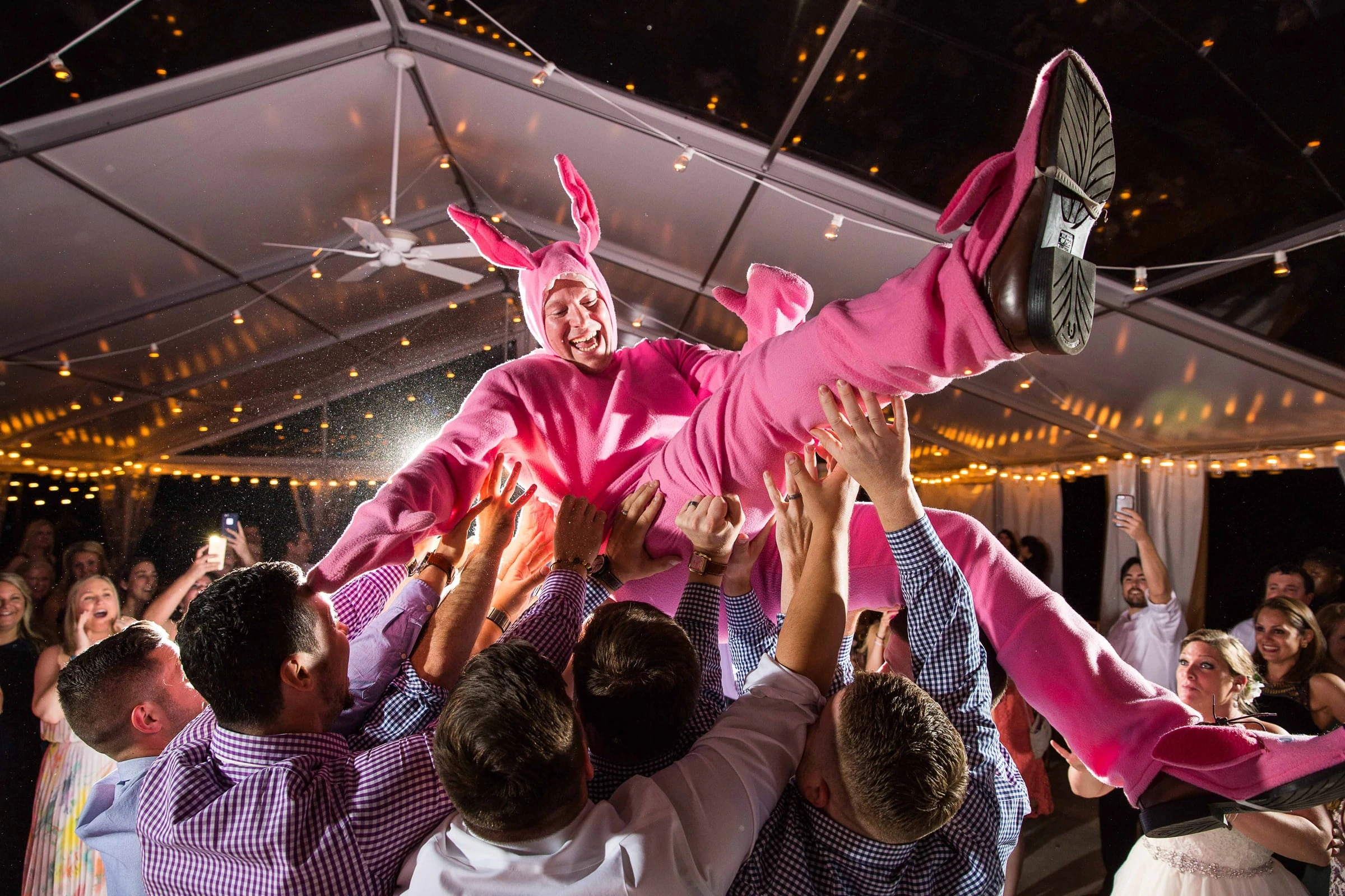 Guests lifting a friend in a pink suit above the dance floor